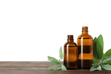 Bottles of essential oil and sage on wooden table against white background