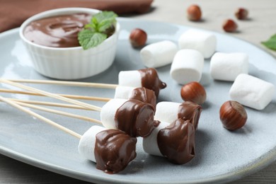 Tasty chocolate dipped marshmallows on plate, closeup