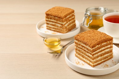 Photo of Delicious layered honey cake served with tea on wooden table. Space for text