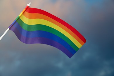 Bright rainbow LGBT flag against cloudy sky