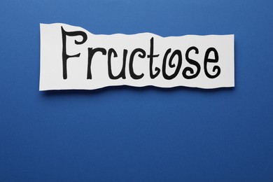 Photo of Paper sheet with word Fructose on blue background, top view. Space for text