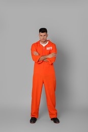 Prisoner in orange jumpsuit on grey background