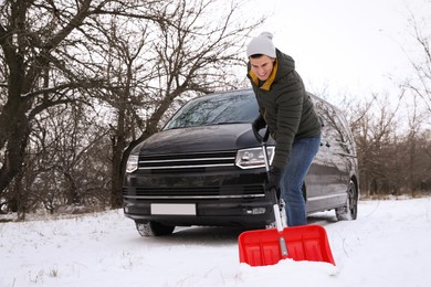 Man removing snow with shovel near car outdoors on winter day