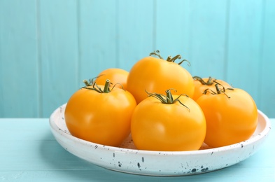 Ripe yellow tomatoes on light blue wooden table