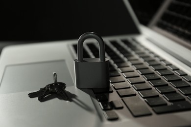 Photo of Metal lock, keys and laptop on dark background, closeup. Cyber security concept