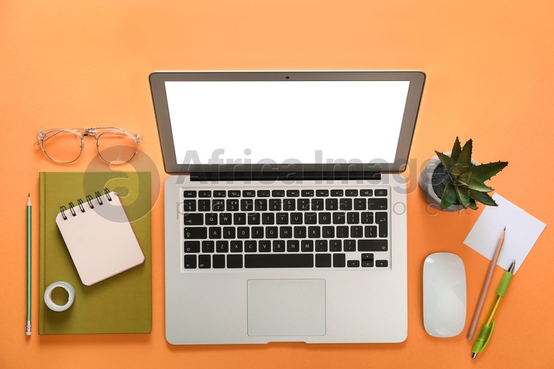 Laptop and office stationery on orange background, flat lay
