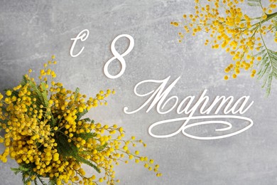Greeting card design. Beautiful mimosa flowers on grey table and text 8 March written in Russian, top view