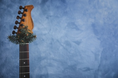 Guitar with fir tree branch on light blue background, space for text. Christmas music