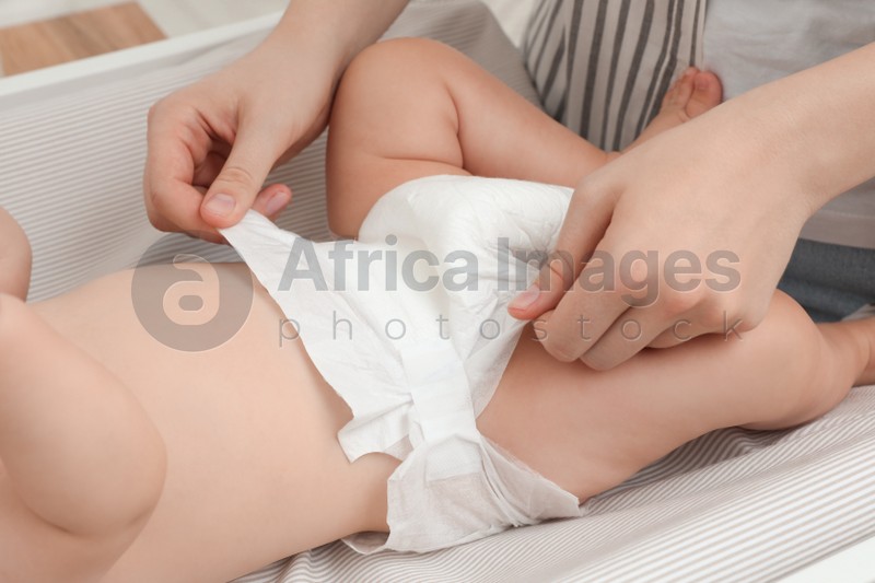 Photo of Mother changing baby's diaper on table, closeup
