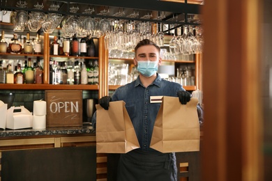 Waiter with packed takeout orders in restaurant. Food service during coronavirus quarantine