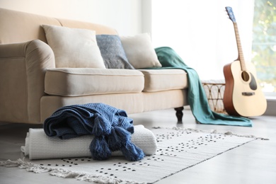 Folded plaids near comfortable sofa in stylish living room interior