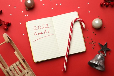 Open planner and Christmas decor on red background, flat lay. Planning for 2022 New Year