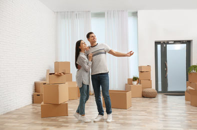 Happy couple in room with cardboard boxes on moving day