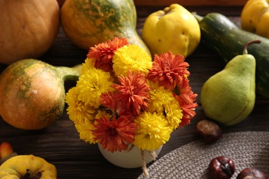 Beautiful chrysanthemum flowers in vase and pumpkins on wooden table, above view. Autumn still life