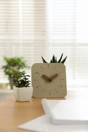 Notebook, clock and houseplants on table indoors