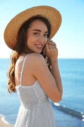 Happy young woman with beach hat near sea