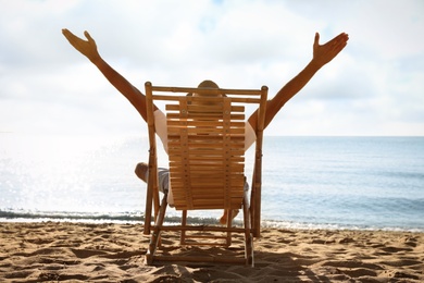 Man relaxing on deck chair at sandy beach. Summer vacation