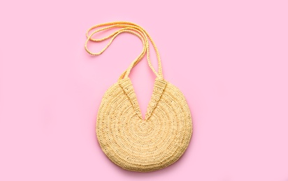 Elegant woman's straw bag on pink background, top view