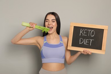 Happy woman holding celery and chalkboard with words Keto Diet on light grey background