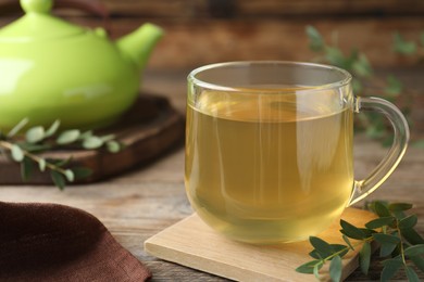 Glass cup of aromatic eucalyptus tea on wooden table, closeup