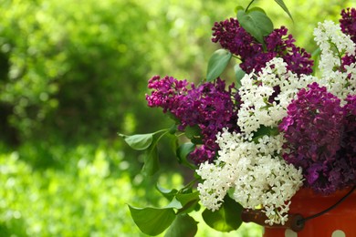 Photo of Bouquet of beautiful lilac flowers in milk can outdoors, closeup. Space for text