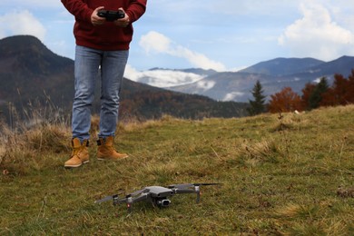Man operating modern drone with remote control in mountains. Space for text