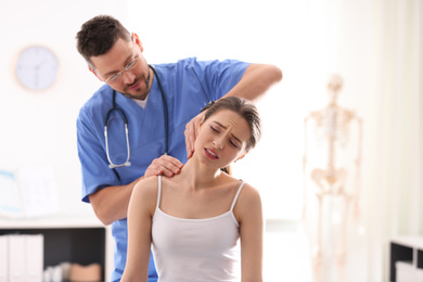 Male orthopedist examining patient's neck in clinic