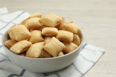 Bowl of sweet crispy corn pads on white wooden table, closeup. Breakfast cereal
