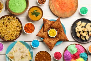 Traditional Indian food and color powders on white wooden table, flat lay. Holi festival celebration