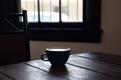 Cup of aromatic coffee on wooden table in cafe