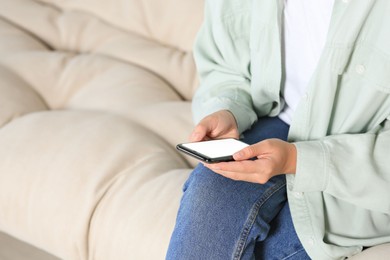 Photo of Woman using smartphone on sofa at home, closeup. Space for text