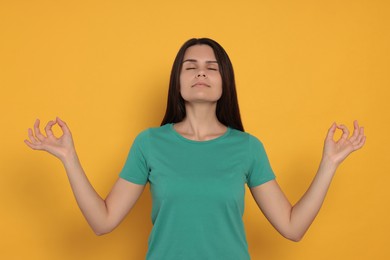 Young woman meditating on orange background. Zen concept