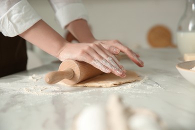 Photo of Woman rolling dough at table in kitchen, closeup
