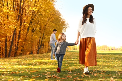 Happy woman with little daughter walking in autumn park