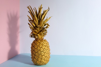 Photo of Golden pineapple on color background, space for text. Creative concept