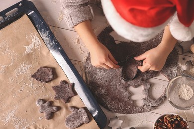 Photo of Little child making Christmas cookies at white wooden table, top view