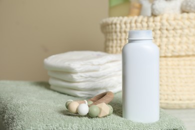 Photo of Bottle of dusting powder, wooden toy, soft towel and diapers on beige background, space for text. Baby cosmetic product