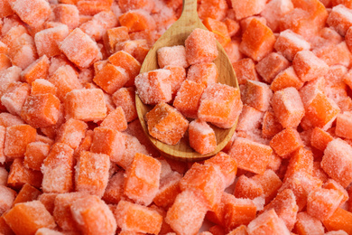 Frozen carrots and wooden spoon, closeup. Vegetable preservation