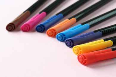 Many colorful markers on pink background, space for text. School stationery