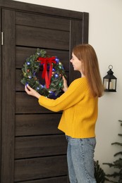 Photo of Woman decorating door with beautiful Christmas wreath