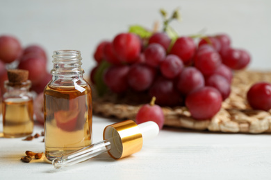 Bottle of natural grape seed oil on white wooden table, space for text. Organic cosmetic