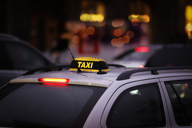 Photo of Taxi car with yellow checkered sign on city street in evening, closeup