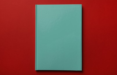 New stylish planner with hard cover on red background, top view