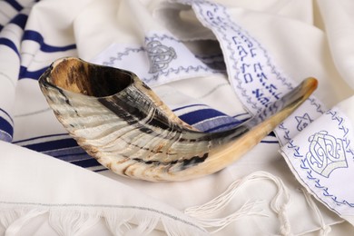 Shofar on tallit with text Blessed Are You, Lord Our God, King Of The Universe,
Who Has Sanctified Us With His Commandments, And Commanded Us To Enwrap Ourselves In Tzitzit. Rosh Hashanah holiday symbols