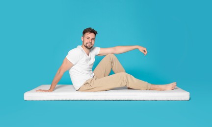 Man posing on soft mattress against light blue background