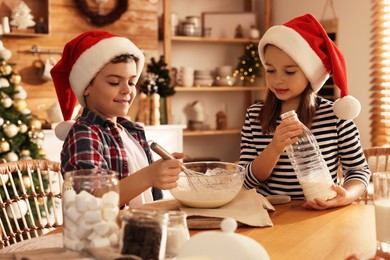 Cute little children making dough for Christmas cookies at home