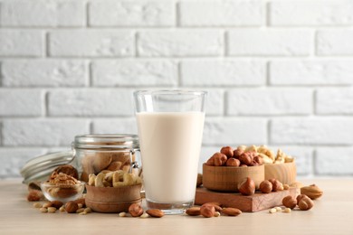 Vegan milk and different nuts on wooden table
