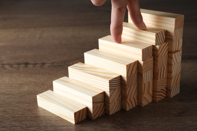 Photo of Woman imitating stepping up on wooden stairs with her fingers, closeup. Career ladder