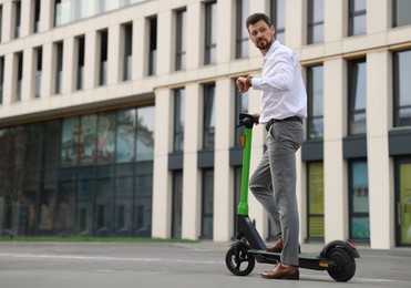 Businessman with modern kick scooter on city street, space for text