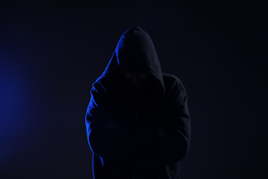 Man in hood on dark background. Cyber crime